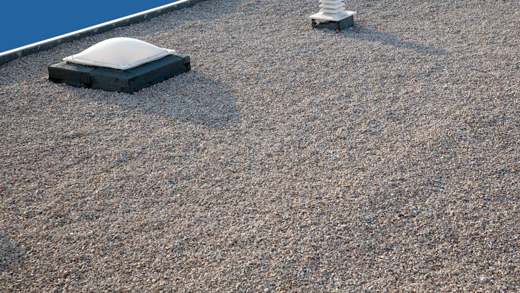 Gravel-ballasted built-up roof with skylight on flat commercial rooftop